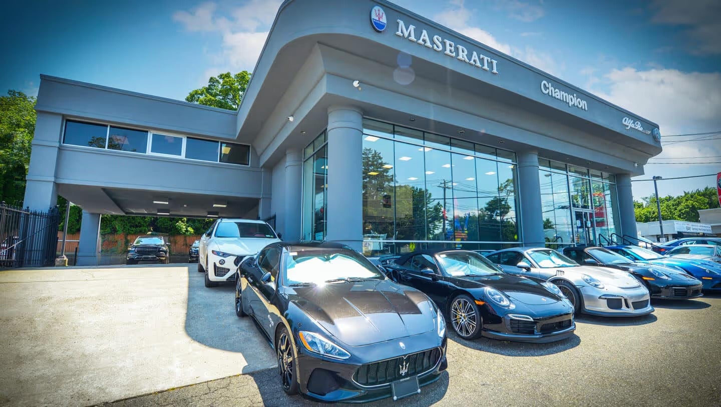 Exterior view of a Maserati dealership with several luxury cars parked outside on a sunny day.